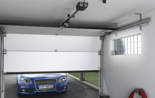 A blue car parked outside a half-open garage door, showcasing a repair service in Appleton.| Badgerland Garage Door Service – Green Bay Garage Door Repair